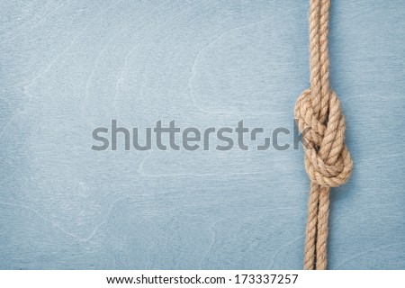 Ship rope knot on blue wooden texture background Royalty-Free Stock Photo #173337257