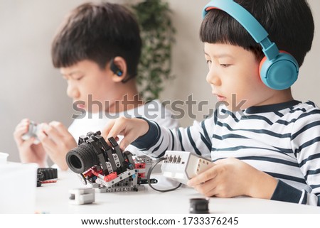 Social distancing & Learning activities, Two Asian brothers boys with headphone assemble and test a robot with EV3 components as school project at home due to school closed and Covid-19 pandemic Royalty-Free Stock Photo #1733376245