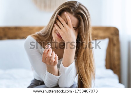 End of marriage and divorce concept. Crying woman covers her face with hand and holds wedding ring, in bedroom Royalty-Free Stock Photo #1733407073