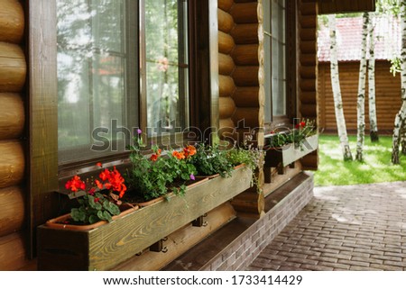 A variety of colorful flowers in boxes on the facade of a rustic wooden house in summer.