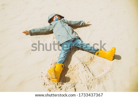 A European boy lies in the pose of an angel on the sand. Recreation, travel, Hiking. Man and nature. Traveller's rest.