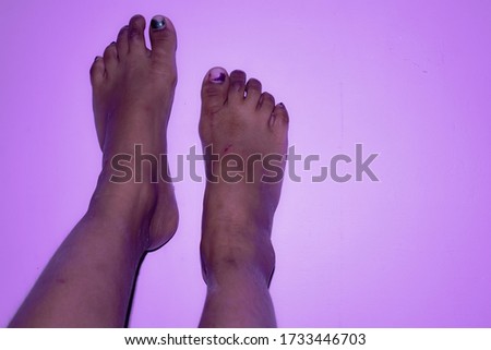 A close up photography beautiful dusk brown skin tone barefoot picture of a girl child on a pink background.