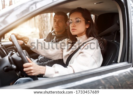 Driving instruction. A young woman learns to drive a car for the first time. Her instructor or boyfriend helps her and teaches her Royalty-Free Stock Photo #1733457689