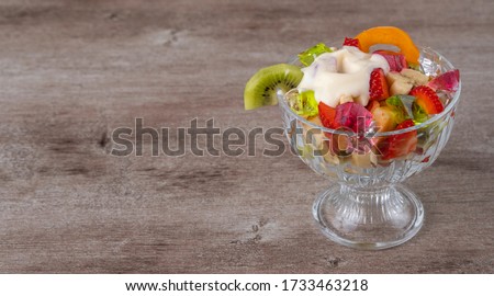 fresh fruit salad in a glass container on a wooden background. richest source of nutrients and vitamins. juicy and fresh berries, the concept of healthy and dietary food.