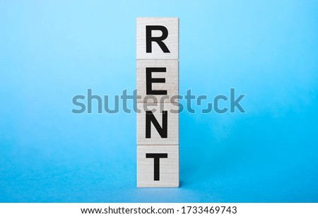 RENT word text inscription on wooden cube blocks on blue background. Copy space. Renting and Housing concept.