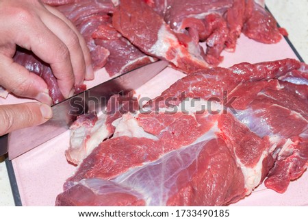 a man cuts raw meat with a knife. Preparation and production of minced meat for sale