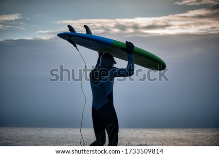 Closeup Surfer silhouette with short surfboard going to the water at sunrise with sky background. Lifestyle and adventure concept.