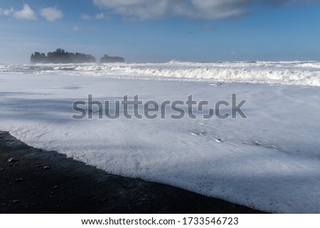 Landscape of white sea foam, waves and distant sea stack at Rialto Beach 