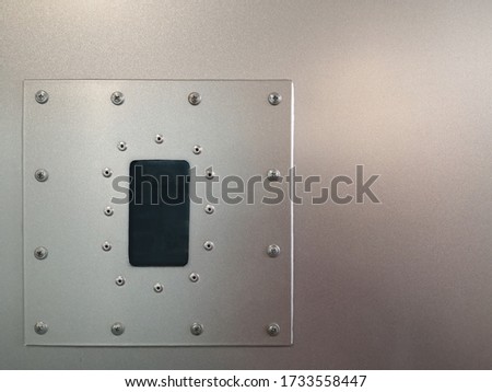 Hidden video camera for surveillance or monitoring. Mecanical engineering pattern with bolts and rivets on perimeter of steel panel. Abstract industrial background with metal powder coating texture.