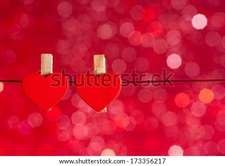 two decorative red hearts hanging against red light bokeh background with space for text, concept of valentine day