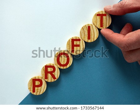 Wood circles with word 'profit' stacking as step stair on paper blue and white background, copy space. Business concept success process.