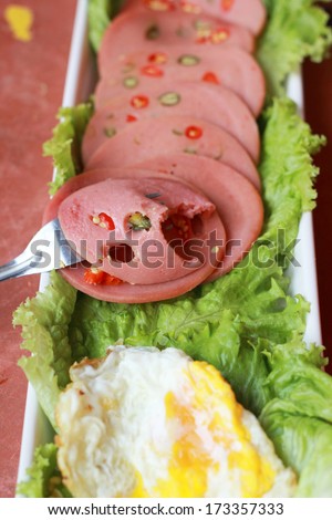 Ham cut into circular discs with red peppers and egg fried.