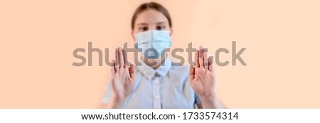 teenage girl on beige background, focus on hands, stop gesture hand, in medical mask, carefully virus and flu virus and disease, stay home, stop pandemic of coronovirus covid 19.