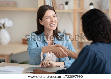 Close up smiling young businesswoman shaking hands with job seeker. Happy successful female manager making deal with new candidate. Professional employee with cv greeting applicant. Royalty-Free Stock Photo #1733597990