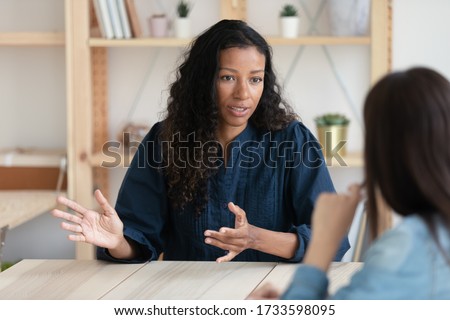 Close up confident african american businesswoman explaining new responsibilities to female applicant. Attractive young diverse woman hr manager talking and introduction company to job seeker. Royalty-Free Stock Photo #1733598095