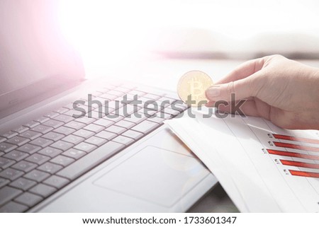 Laptop, graphics and bitcoin in the hand. Online commerce. Business still life.