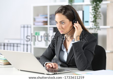 Confused telemarketer woman looking at laptop sitting on a desk at the office Royalty-Free Stock Photo #1733611259