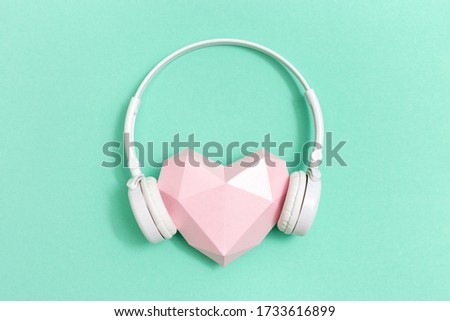 Volumetric paper pink heart in white headphones.  Concept for music festivals, radio stations, music lovers.  Live with music. Minimal style.  