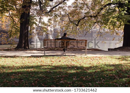 Woman with river in front of her while sitting on a park bench