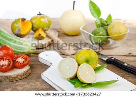 Close up of citrus fruits in wooden background. Fresh lemon, pear, persimmons, and tomato on table