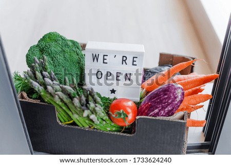 End of quarantine lockdown. Lightbox with greeting text message We're open and Fresh greens and vegetables box. Welcoming grocery shop clients after coronavirus Covid-19 pandemic outbreak