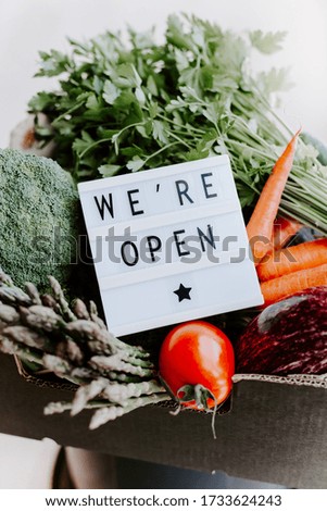 End of quarantine lockdown. Lightbox with greeting text message We're open and Fresh greens and vegetables box. Welcoming grocery shop clients after coronavirus Covid-19 pandemic outbreak