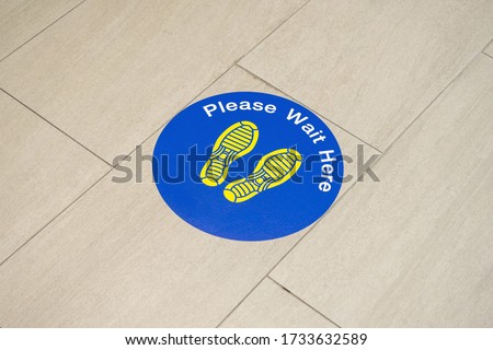 footprint sign for stand in shopping mall, supermarket. Social distancing with COVID-19 coronavirus crisis. yellow footprint sign with text caution social distance