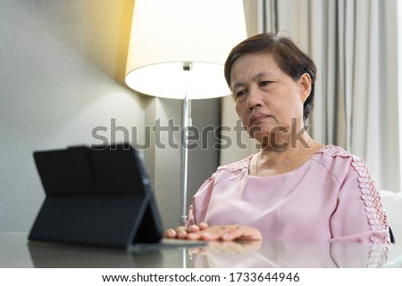 Stressed Asian Senior woman consulting with Doctor about her Coronavirus or covid 19 symptoms via internet technology. Old female making video call with physician via digital tablet during quarantine. Royalty-Free Stock Photo #1733644946