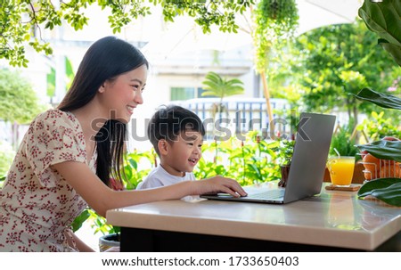 Asian mother teach her son by note book computer in garden at home, this image can use for education, home, park and family concept.