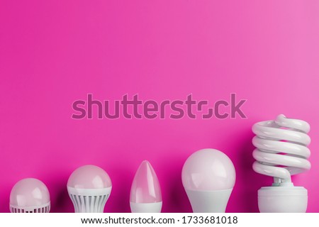 A special Light bulb stands out from the group of ordinary white light bulbs on a pink background.
