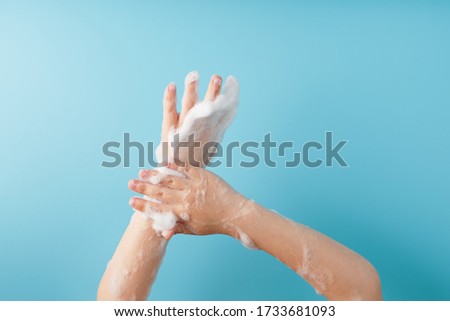 Children's hands in soap suds, on a blue background, top view.