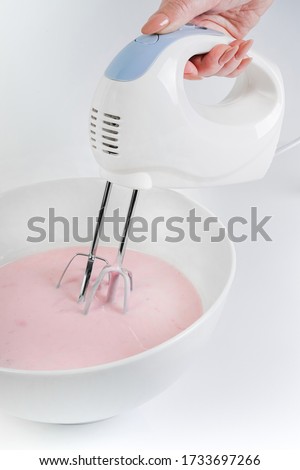 mixer whips pink cream for cake. small appliances for the kitchen. mixer whips cake cream, healthy food, smoothie close-up top view. transparent plate with a mixer. natural cream recipe               