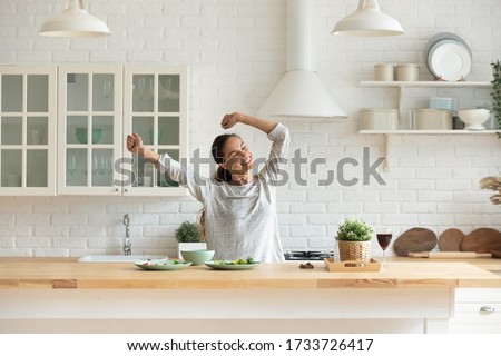 Happy millennial girl preparing healthy breakfast having fun in bright modern kitchen at home, overjoyed young woman cooking in new house or apartment feel excited moving relocating to own dwelling Royalty-Free Stock Photo #1733726417