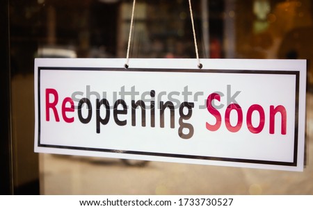 Reopening Soon Signage borad infront of Businesses or Restaurant door after covid-19 or coronavirus outbreak - Concept of back to business after pandemic. Royalty-Free Stock Photo #1733730527