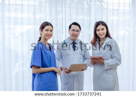 Successful team of medical doctors are looking at camera and smiling while standing in hospital