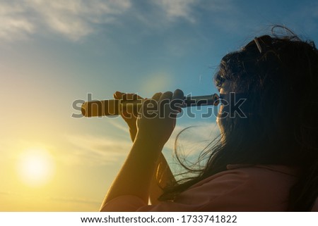 Girl looks in a monocular telescope on a sunset background. Business concept idea, look into the future, peep, see a new one. Outdoors!