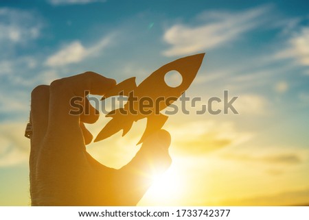 Launch rocket in businessman hand on sunset sky background. Business concept idea, partnership, innovation, success and achievement.