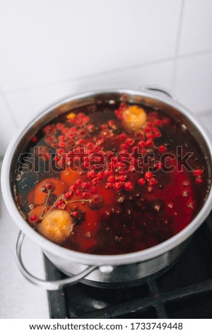 Cooking a delicious compote of apricot, apples, cherries, raspberries. Fresh fruits are boiled in boiling water in a metal pan on the stove. Photography, concept.