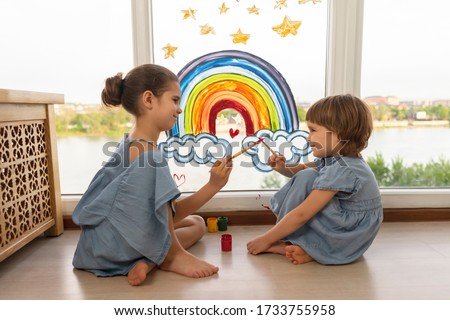 children at home draws a rainbow on the window. Girls kids create artist paints. let's all be well.Flash mob society community on self-isolation quarantine pandemic coronavirus.