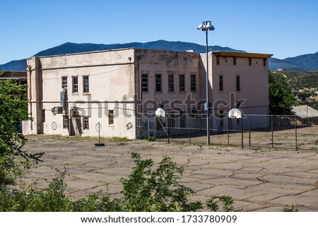 Old Abandoned Two Story School Building With Overgrown Play Yard