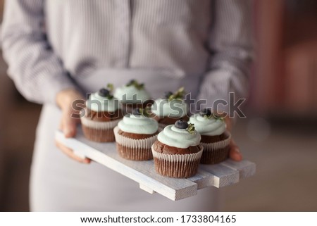 women's hands and cupcakes with blueberries on the Board