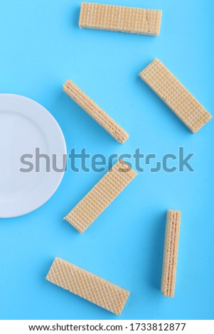 Tasty wafer sticks on Blue background, flat lay. Sweet food