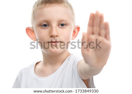 Little boy put a palm in the stop sign on white isolated background. Backlight horizontal Photo.
