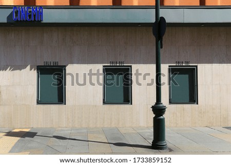 Turin, Italy. Cinema sign on a facade and three empty green billboard showcase for movie poster or show advertising along the sidewalk. Copy space available.