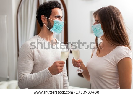 Man and Woman hands toasting with Champagne wearing a mask, coronavirus concept
