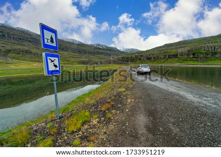 Cars parked on a dirt road In the midst of great nature Panoramic view of the valley and lake In the summer of countryside in Iceland.
