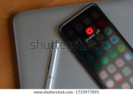 A mobile device powering down, resting on a laptop Royalty-Free Stock Photo #1733977895