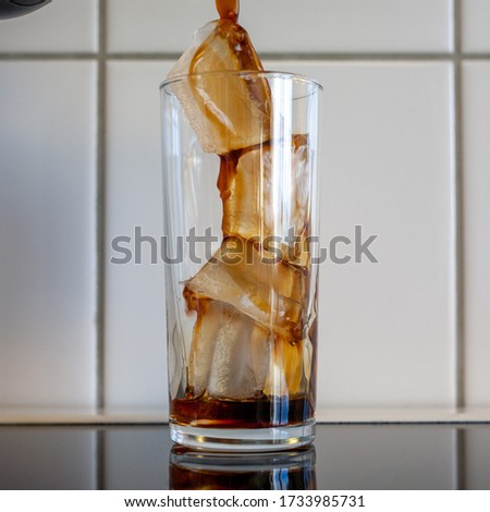 A beautiful vertical shot of a coffee pouring into the glass full of ice