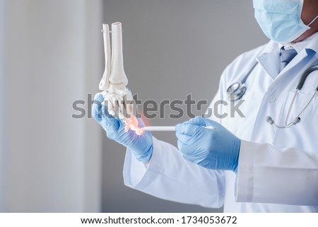 Close-up of pictures of a male orthopedic doctor or orthopedic doctor Wear a medical mask and medical gloves. Going to analyze the cause of ankle bone degeneration In his office at the hospital