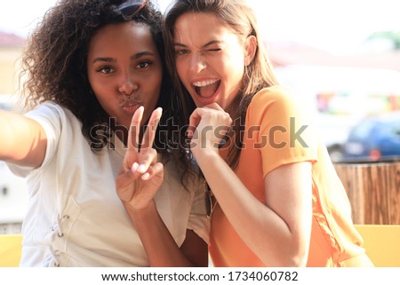 Cute young girls friends having fun together, taking a selfie while sitting at cafe.